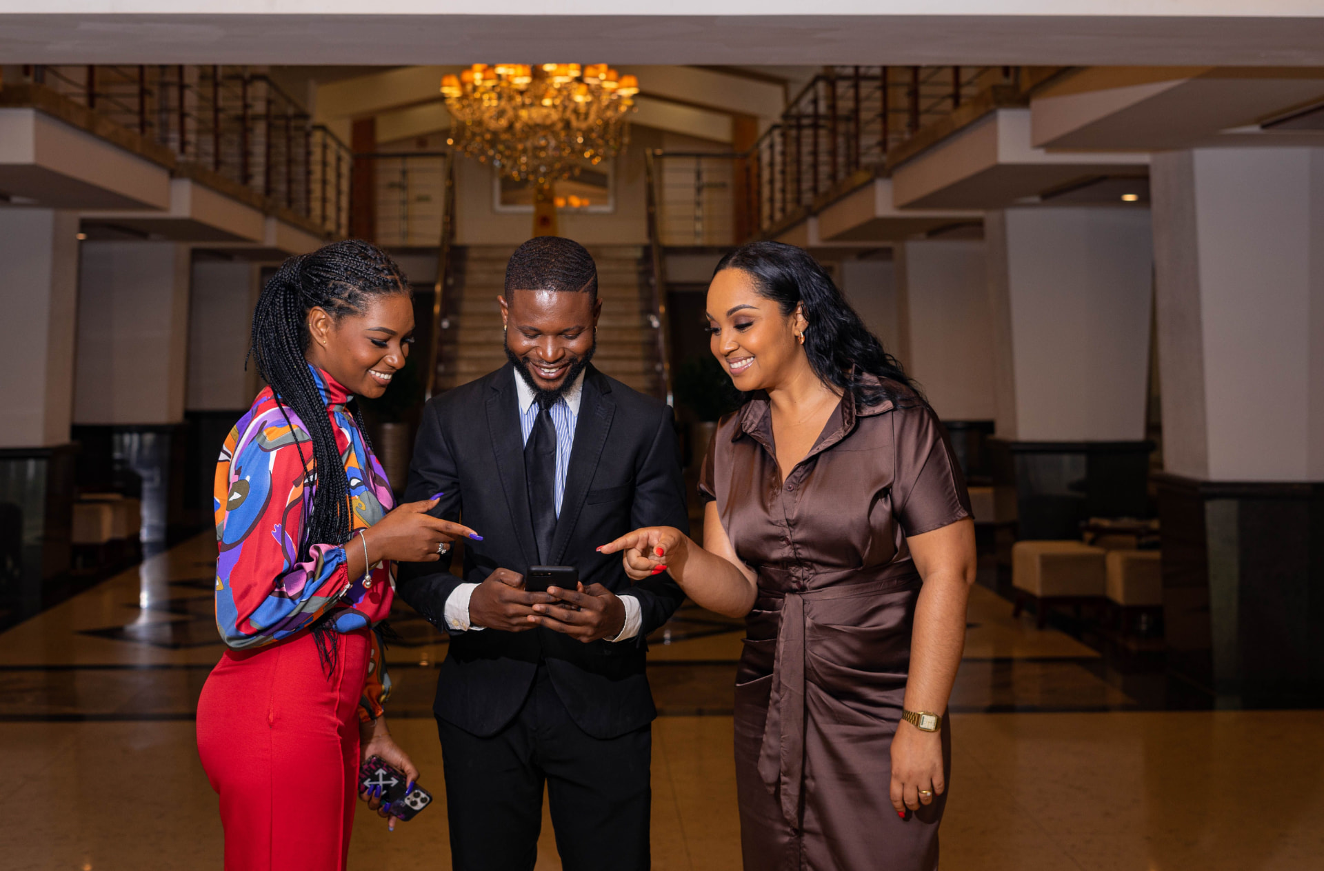 Three professionals smiling and looking at a phone together