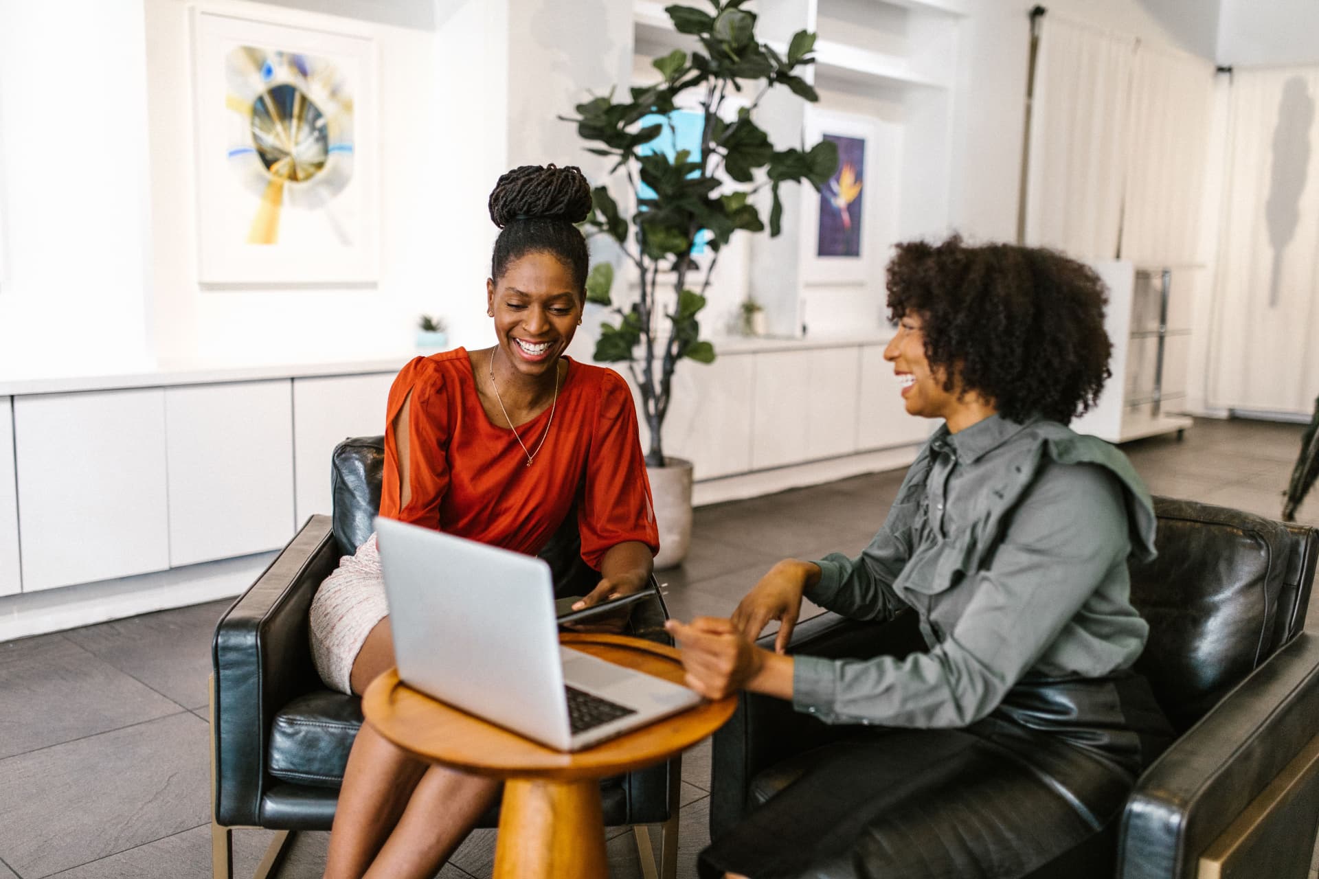 Two women seated together discussing work on a laptop